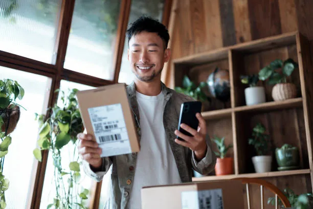 A seller holding a wrapped parcel in front of a shelf of stock