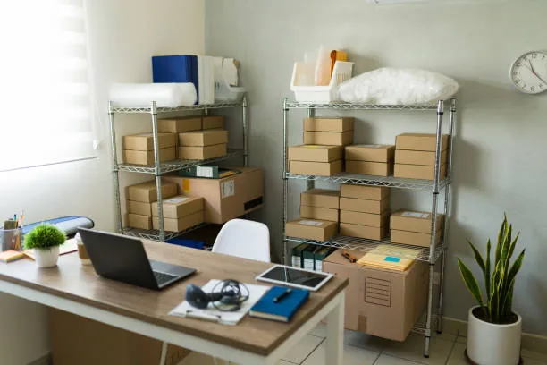 A spare room set up with shelving, stock and a laptop