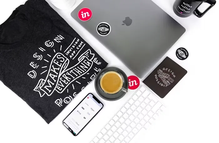 A printed shirt laid out beside a laptop and stickers